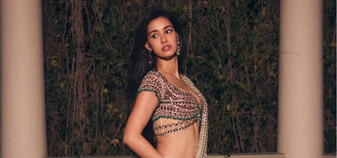 Disha Patani’s ivory pre-draped sari is teamed with a bejewelled blouse with 8,000 gemstones